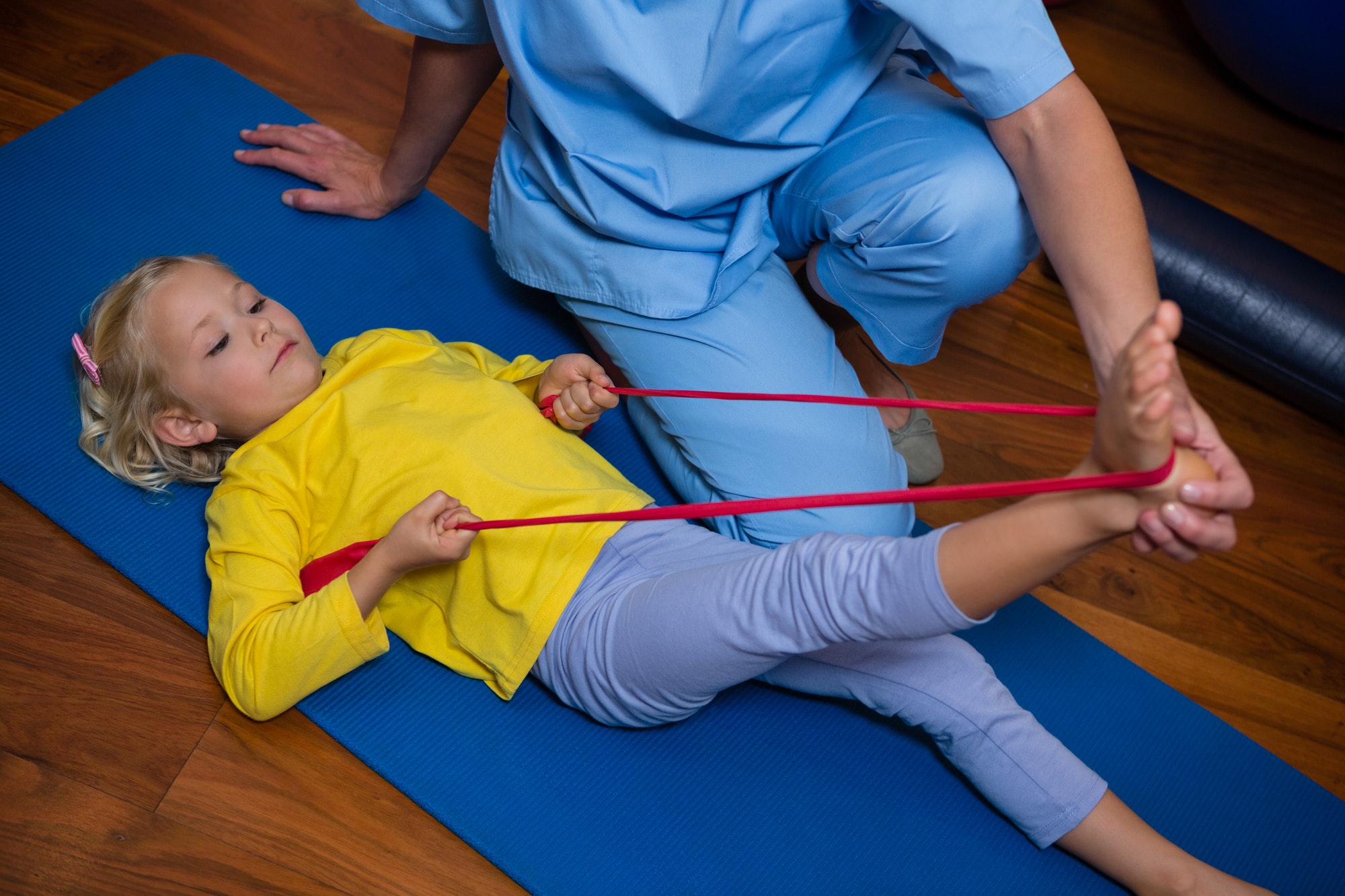 Female physiotherapist assisting a girl patient while exercising