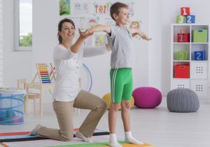 Physiotherapist exercising with a school-boy